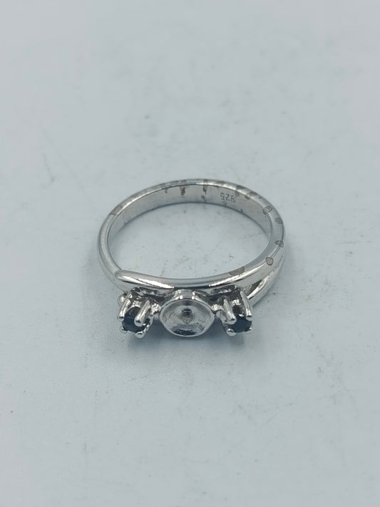 Eleganter Silberring mit dunklen Seitensteinen und mittiger Fassung