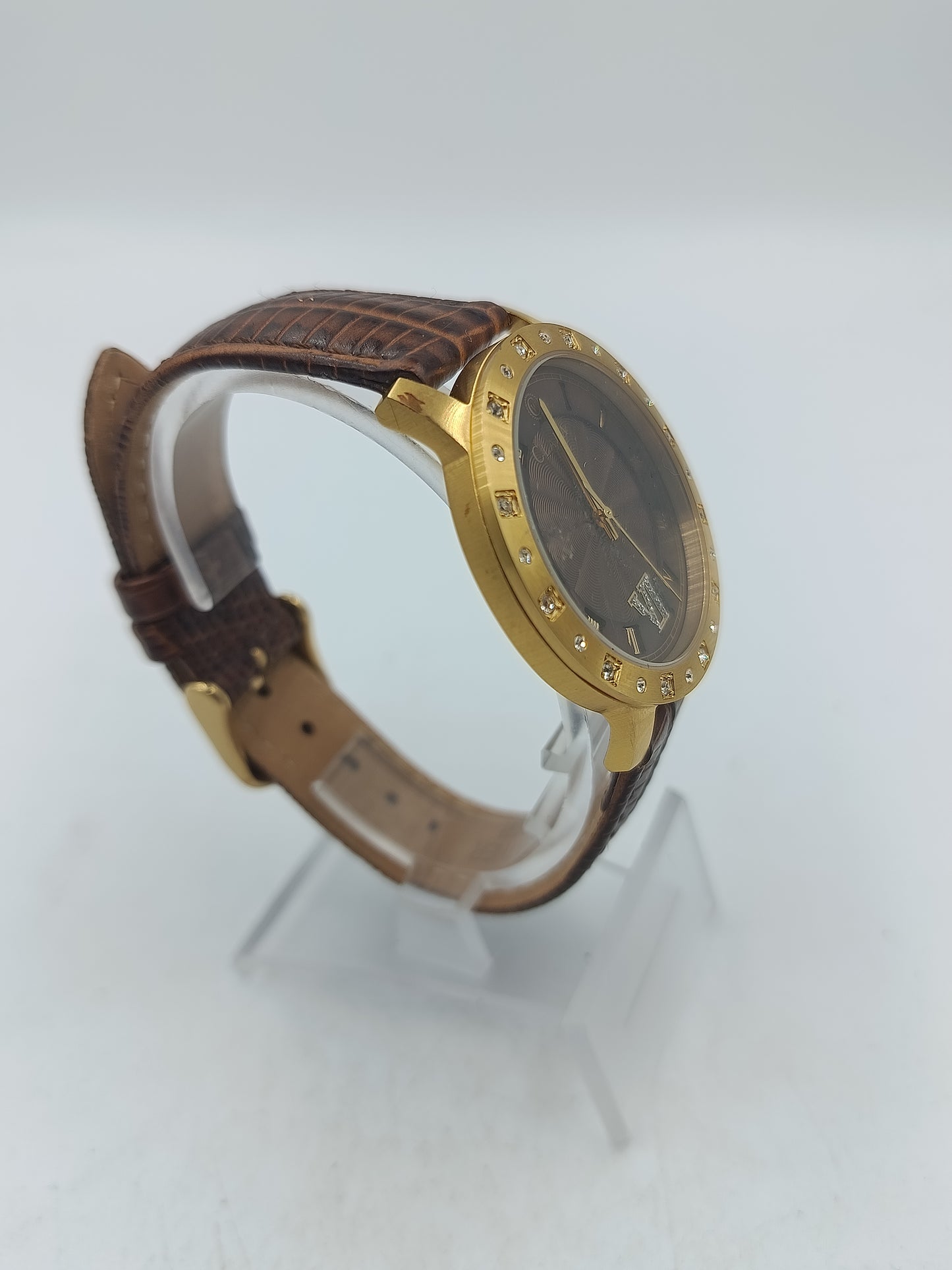 Elegante Armbanduhr mit braunem Lederband goldfarbenem Gehäuse und funkelnden Ziersteinen