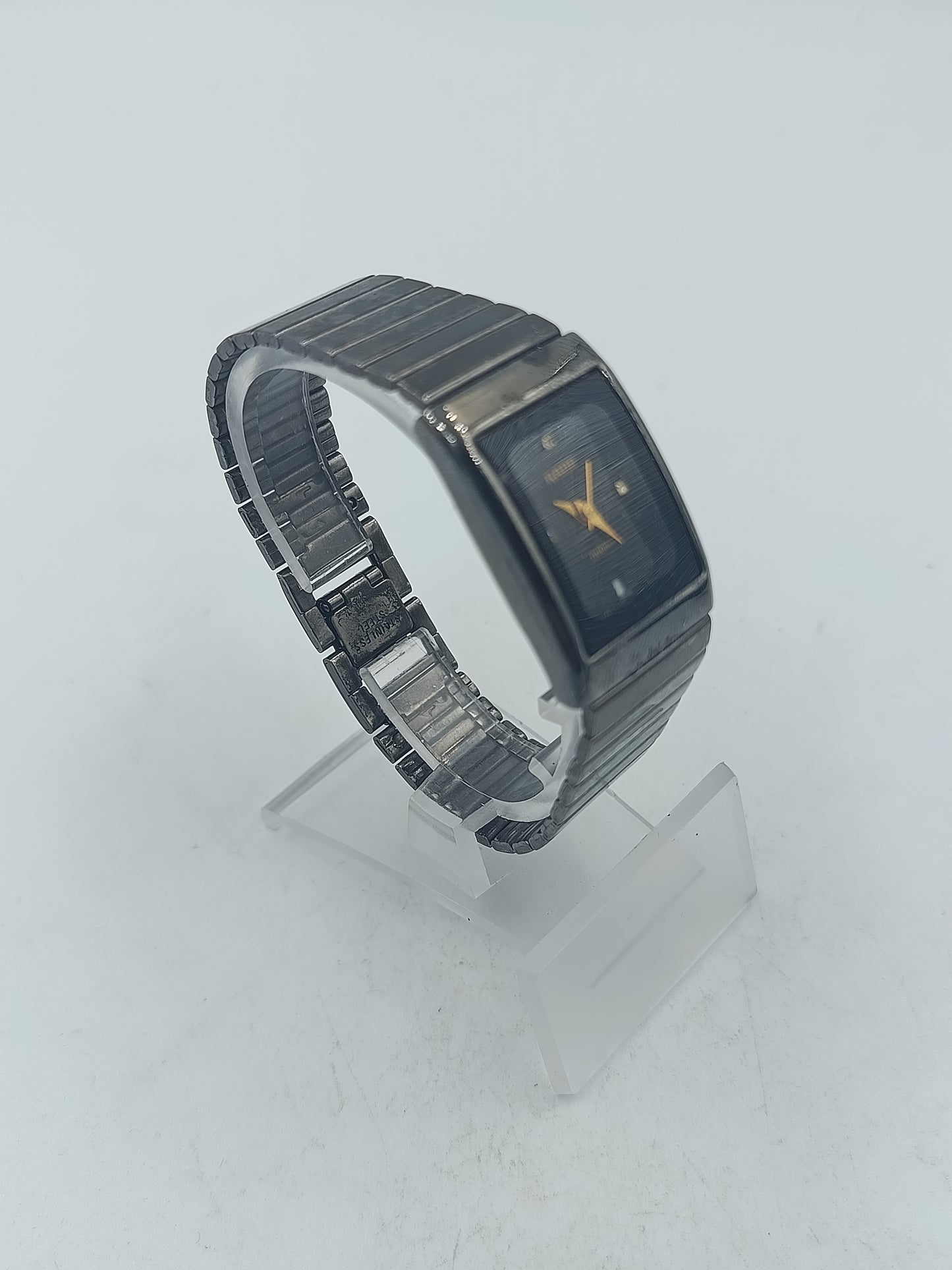 Rechteckige Armbanduhr mit schwarzem Zifferblatt und elastischem Metallarmband im klassischen Design