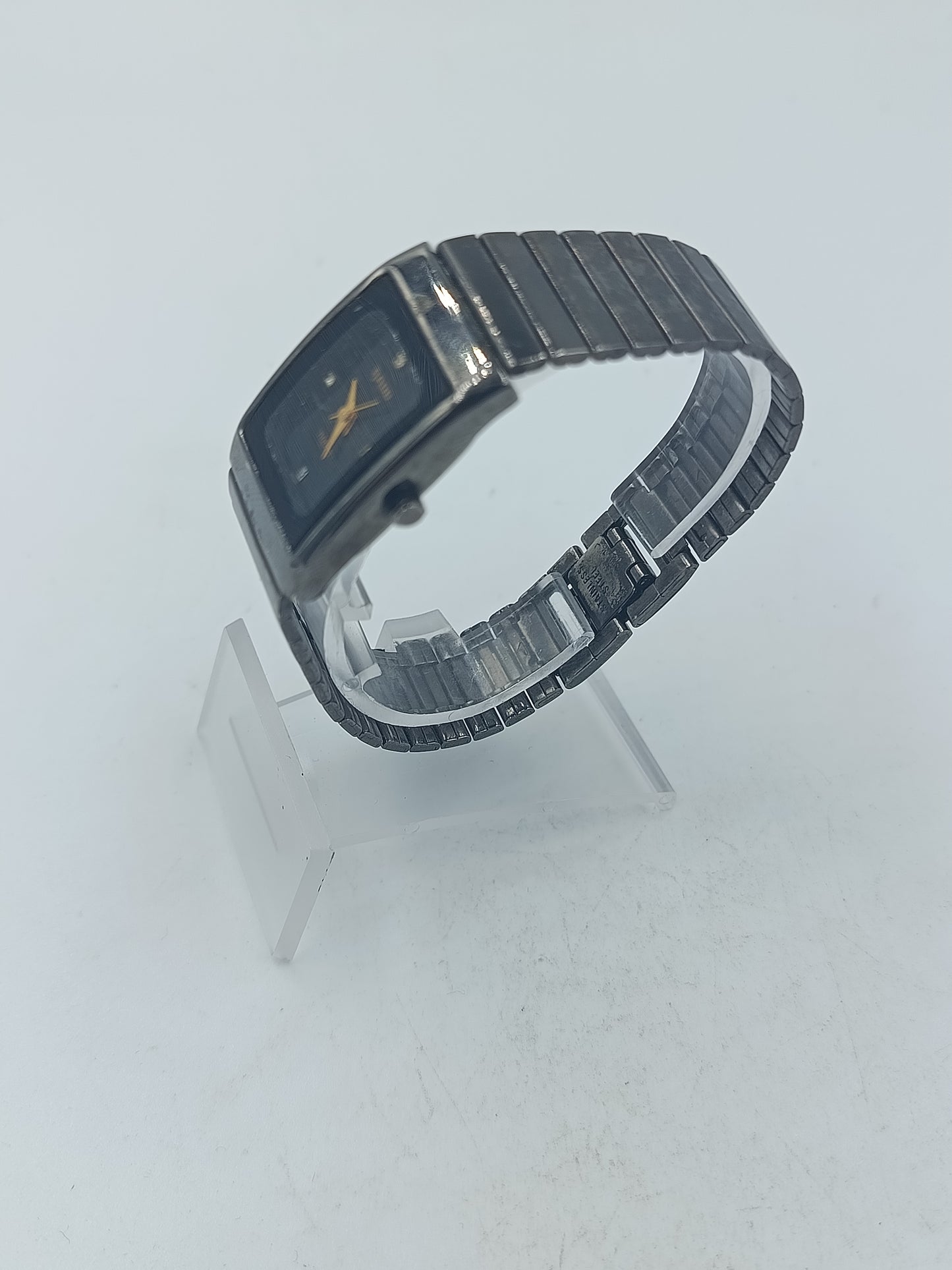 Rechteckige Armbanduhr mit schwarzem Zifferblatt und elastischem Metallarmband im klassischen Design