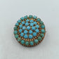 Runde Brosche in goldfarbener Optik mit türkisen Glassteinen im Vintage Stil