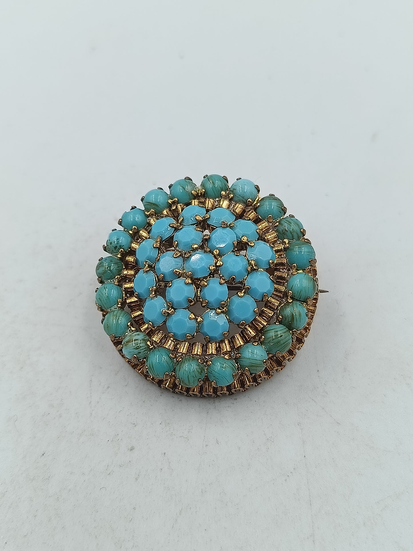 Runde Brosche in goldfarbener Optik mit türkisen Glassteinen im Vintage Stil