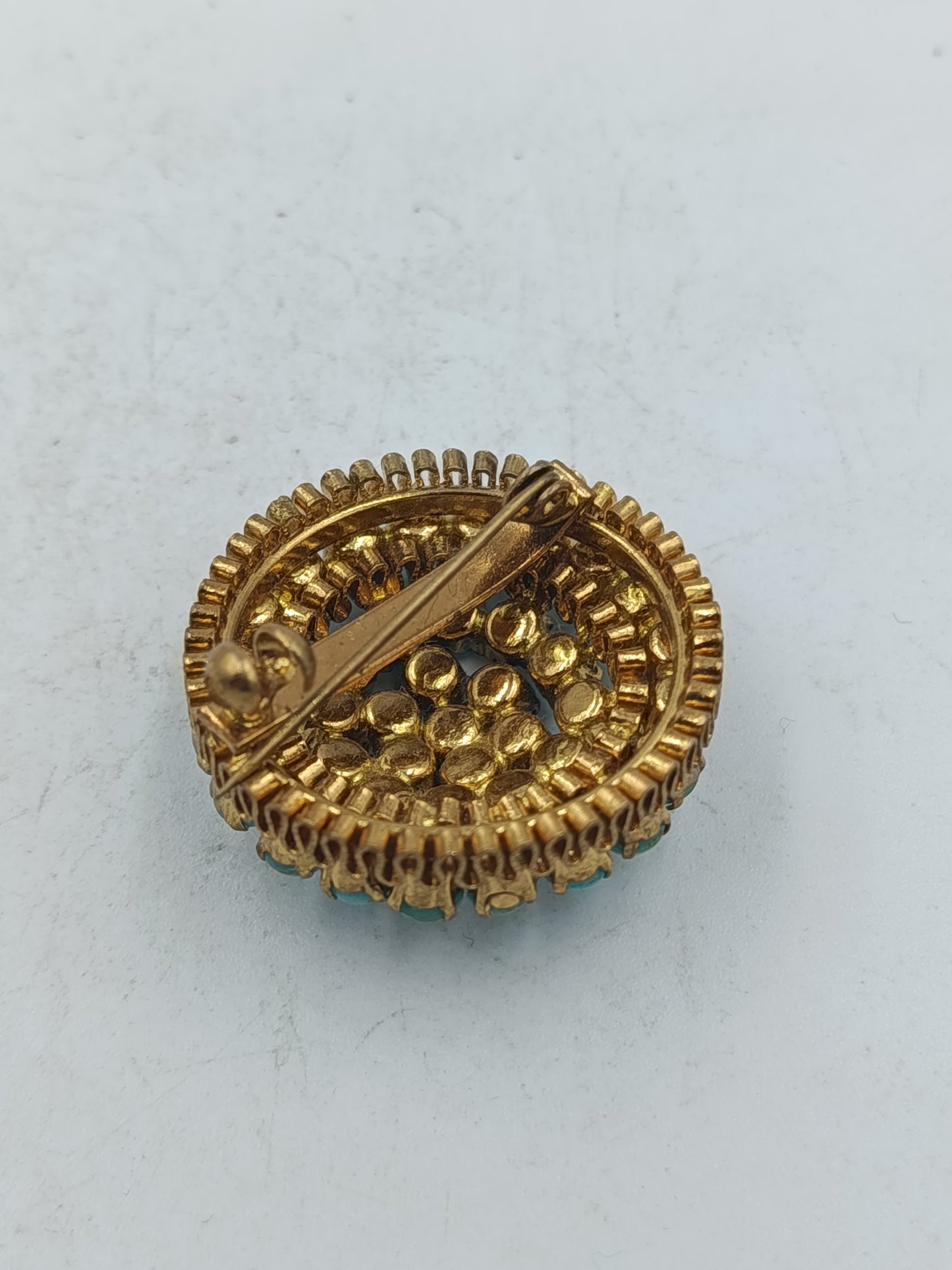 Runde Brosche in goldfarbener Optik mit türkisen Glassteinen im Vintage Stil
