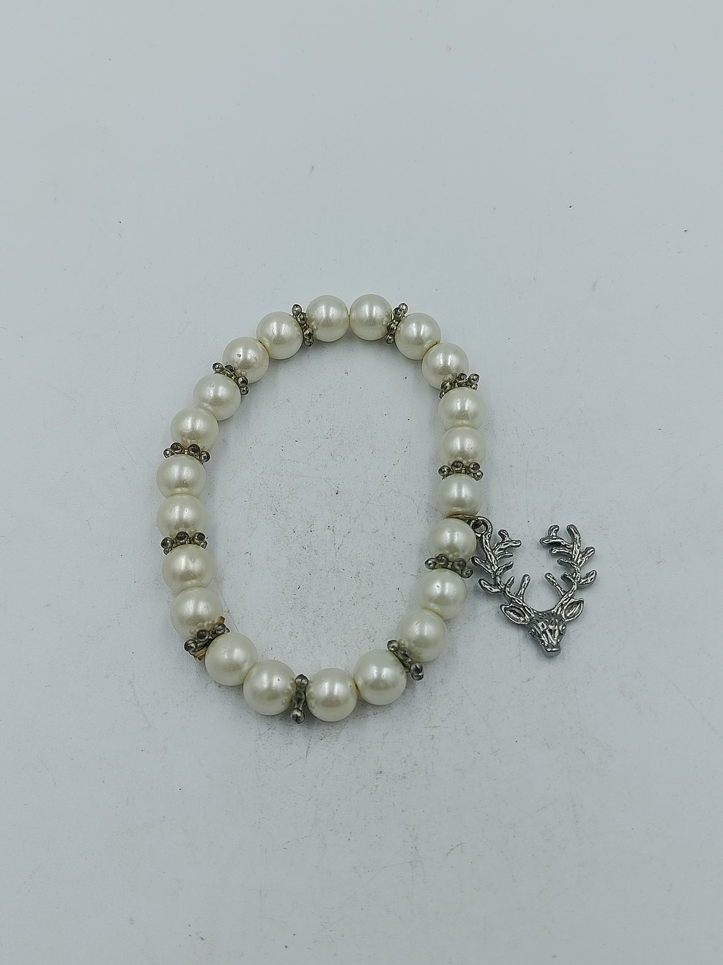 Elastisches Perlenarmband in Creme mit dekorativem Hirschanhänger in silberfarbener Optik