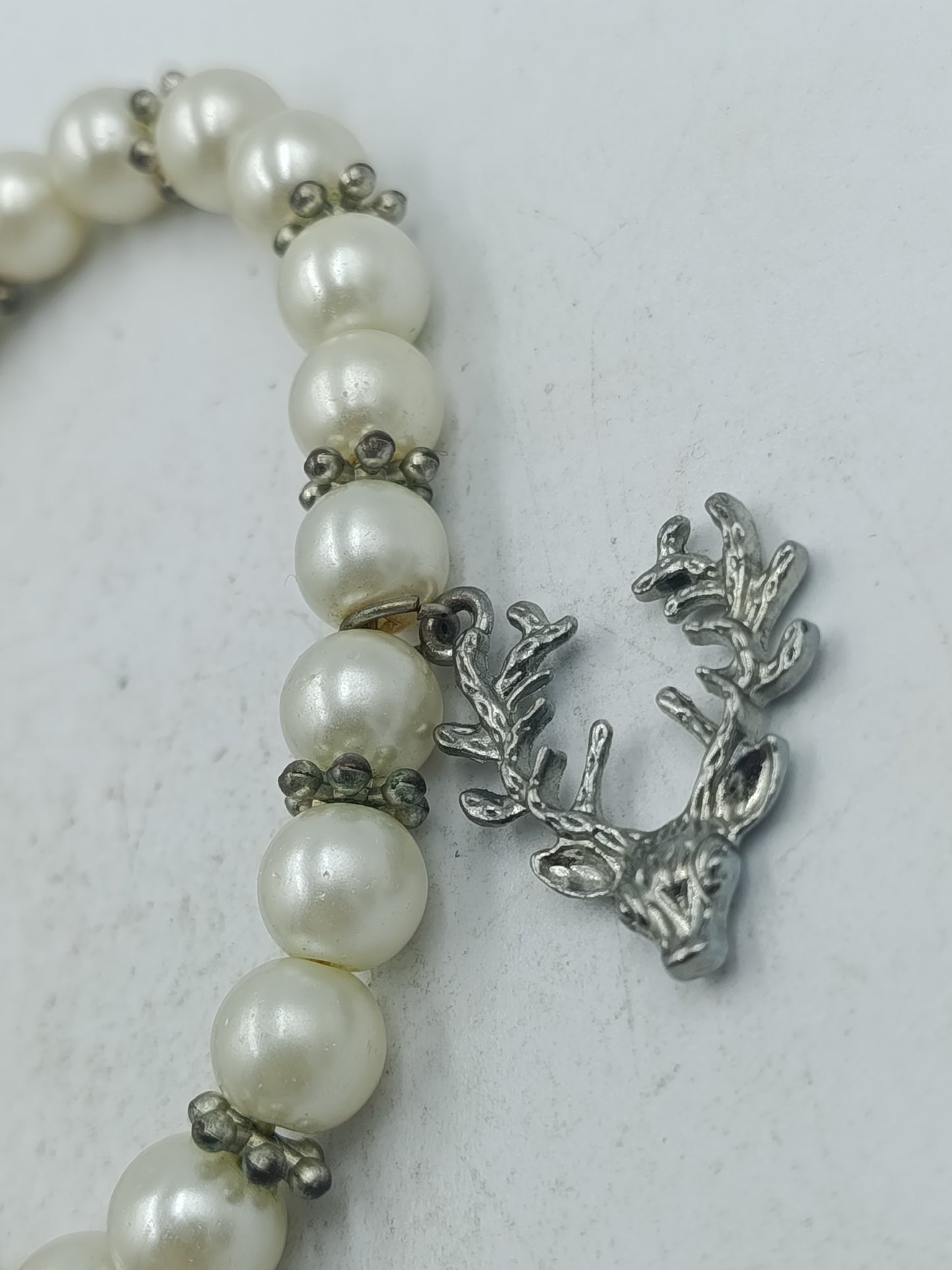 Elastisches Perlenarmband in Creme mit dekorativem Hirschanhänger in silberfarbener Optik