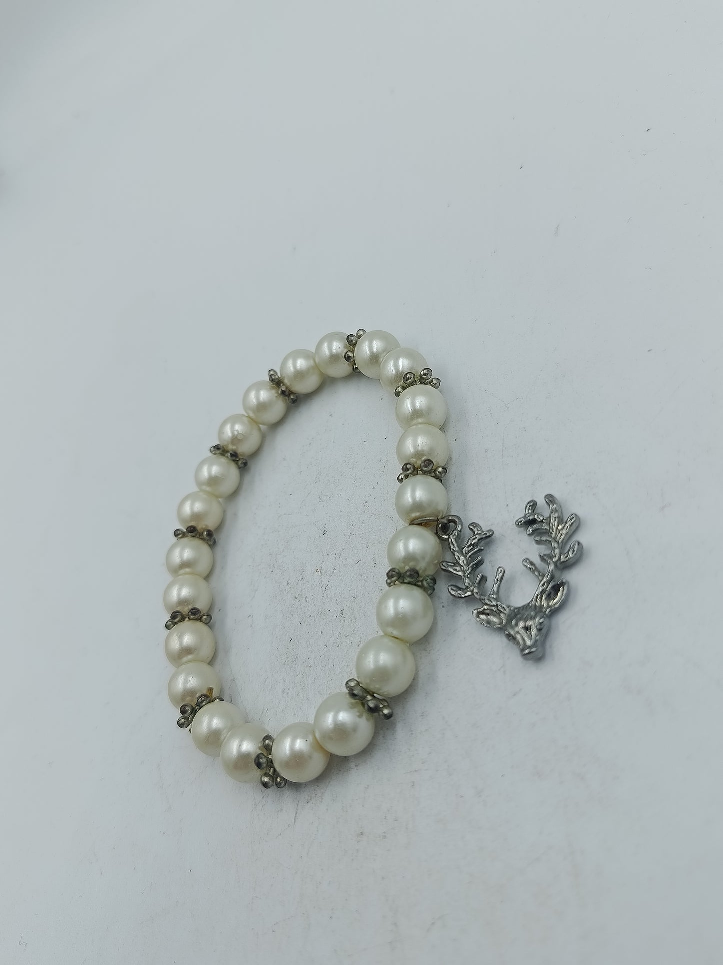 Elastisches Perlenarmband in Creme mit dekorativem Hirschanhänger in silberfarbener Optik