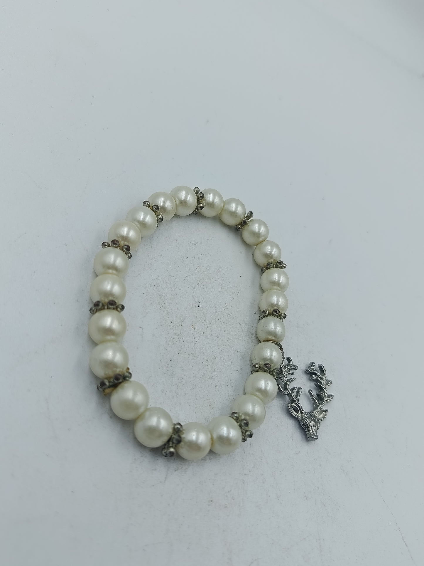 Elastisches Perlenarmband in Creme mit dekorativem Hirschanhänger in silberfarbener Optik