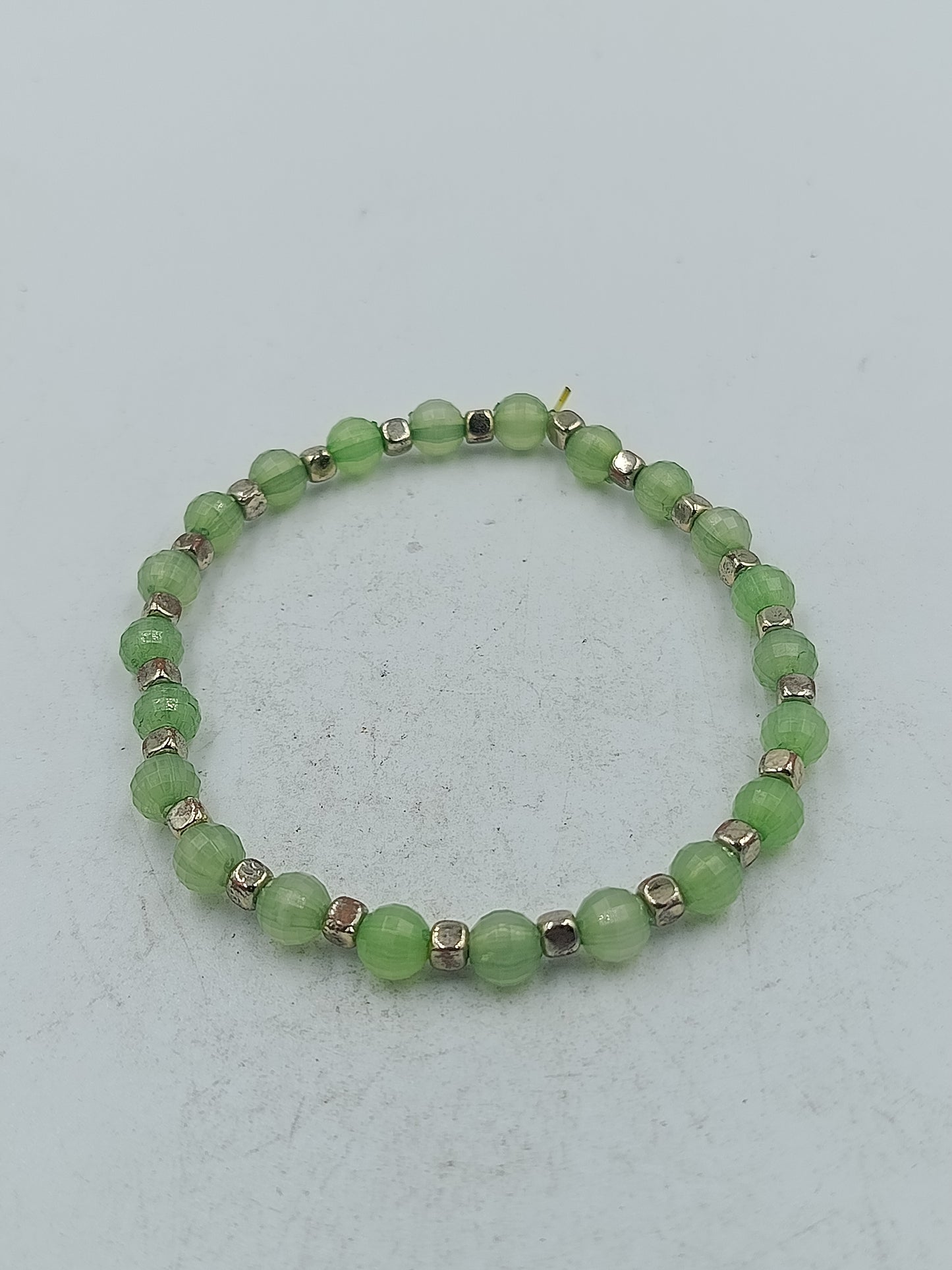 Elastisches Armband mit grünen facettierten Perlen und silberfarbener Optik