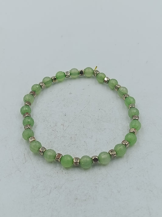 Elastisches Armband mit grünen facettierten Perlen und silberfarbener Optik