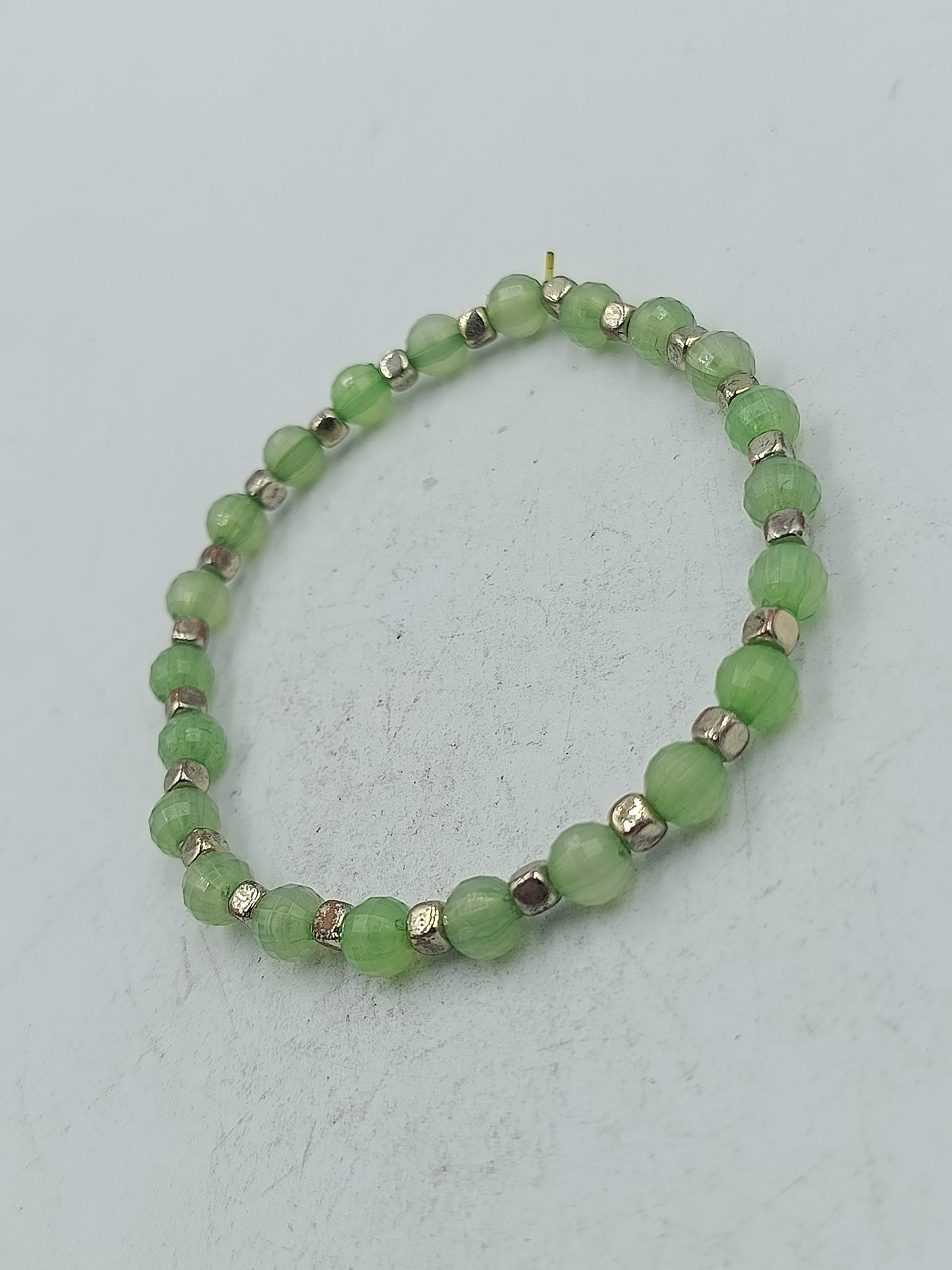 Elastisches Armband mit grünen facettierten Perlen und silberfarbener Optik