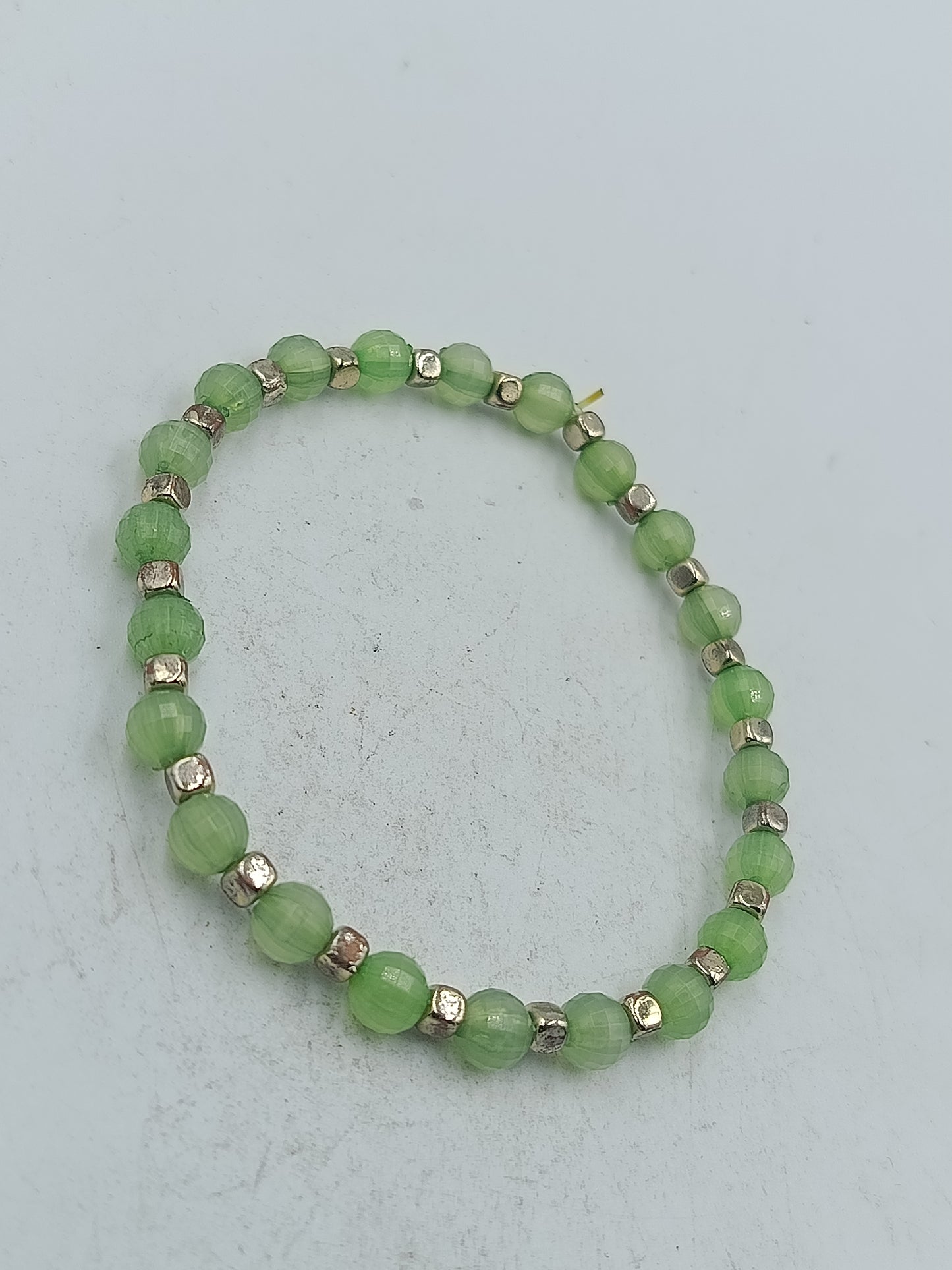 Elastisches Armband mit grünen facettierten Perlen und silberfarbener Optik