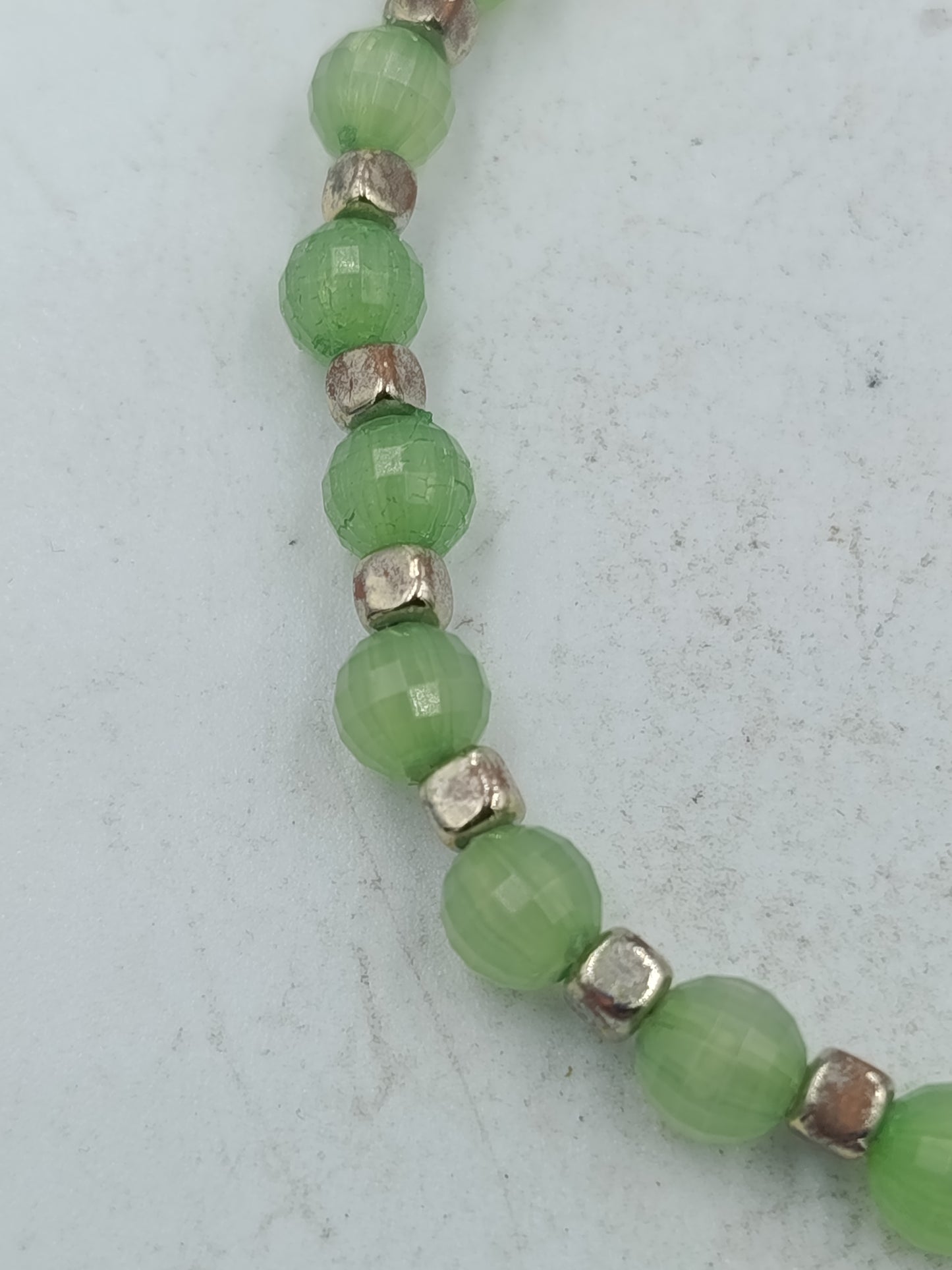Elastisches Armband mit grünen facettierten Perlen und silberfarbener Optik