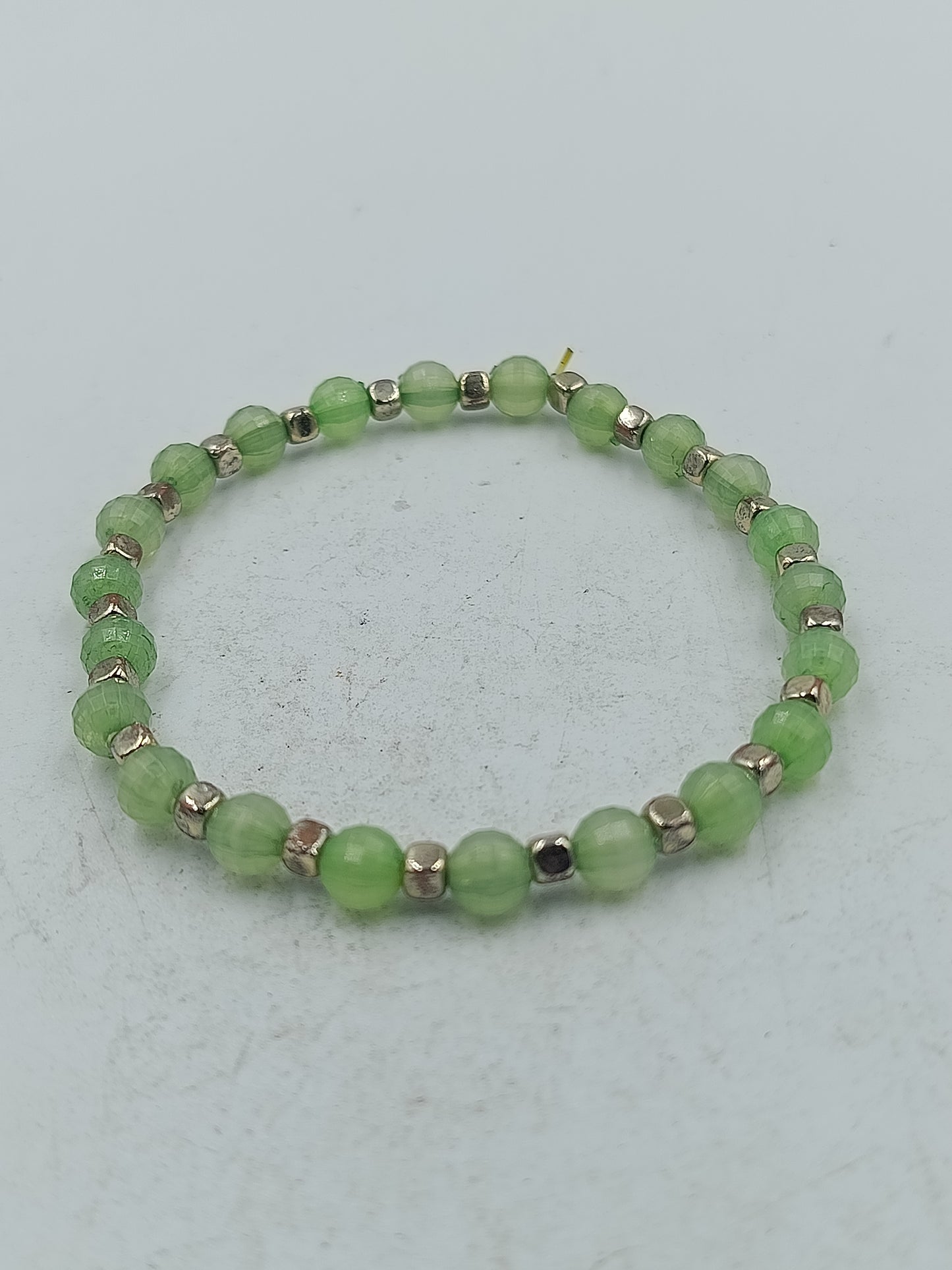 Elastisches Armband mit grünen facettierten Perlen und silberfarbener Optik