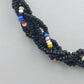 Bunte Glasperlenkette mit schwarzer Grundfarbe und dekorativem Mittelstein