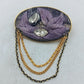 Ovale Brosche mit violettem Blattmotiv und goldfarbenen Zierketten