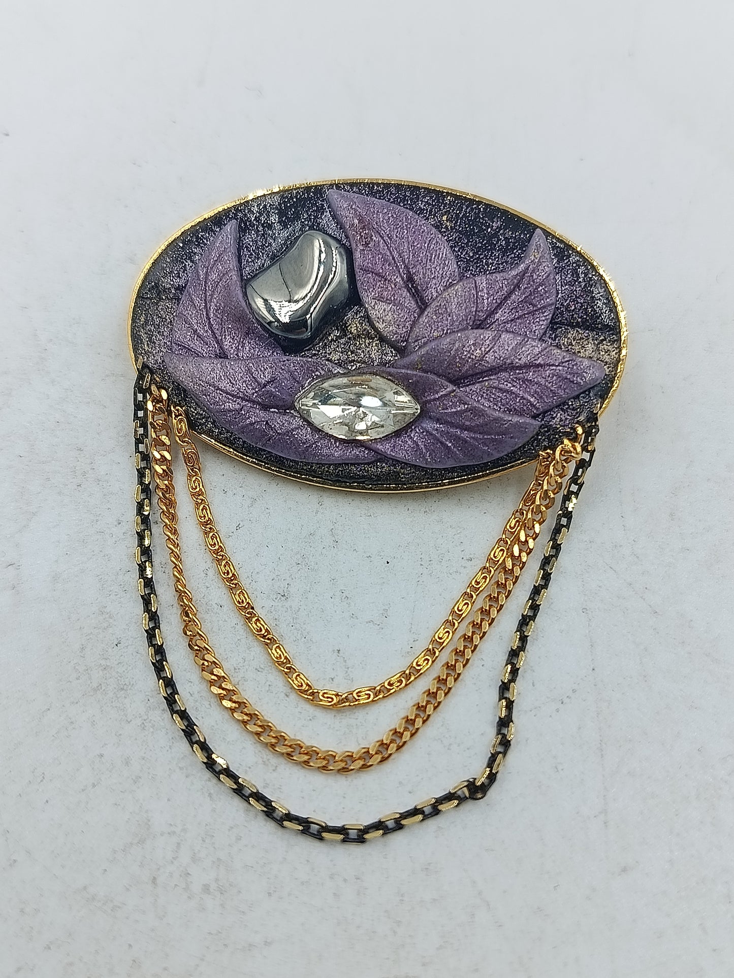 Ovale Brosche mit violettem Blattmotiv und goldfarbenen Zierketten