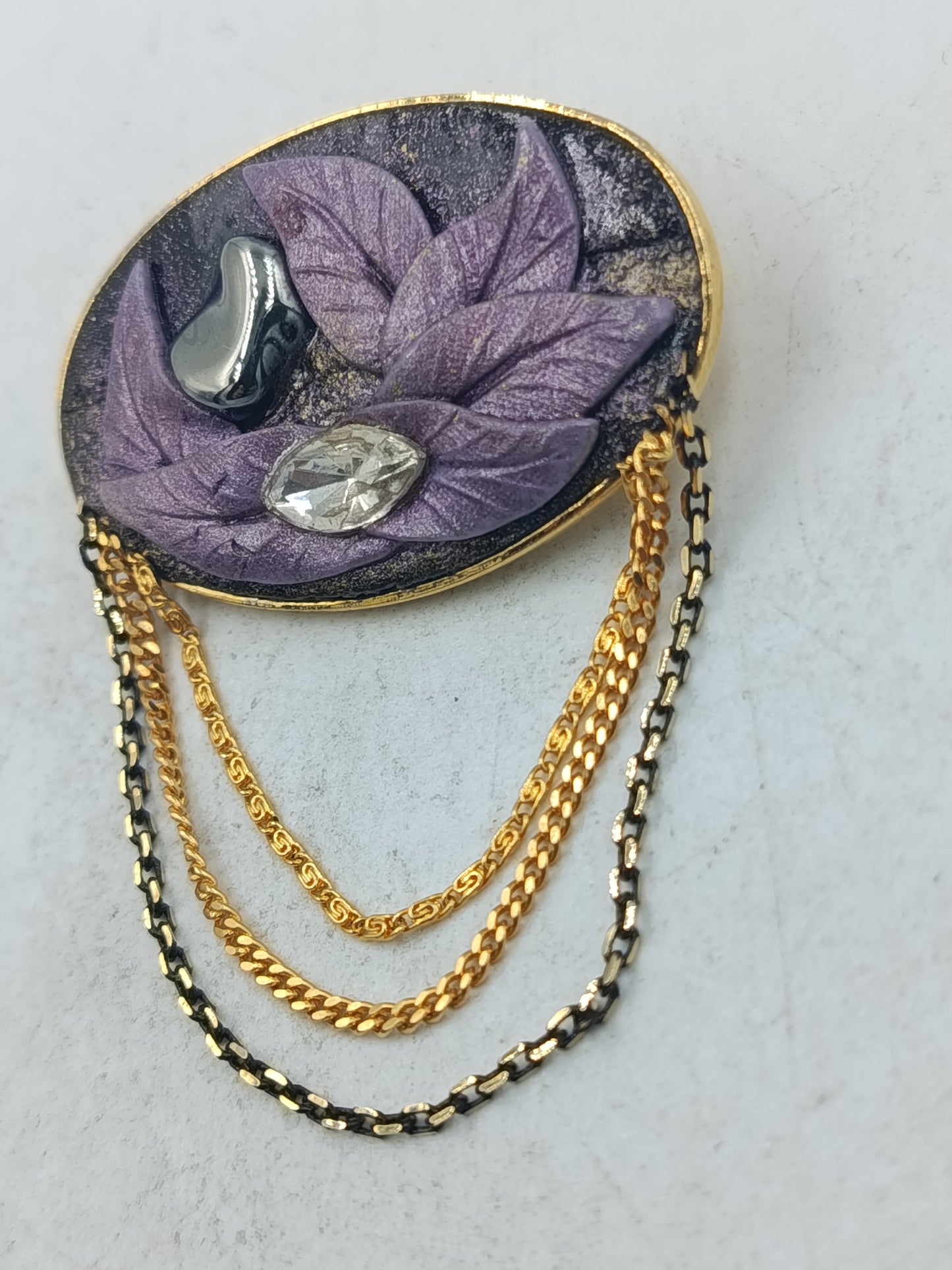 Ovale Brosche mit violettem Blattmotiv und goldfarbenen Zierketten
