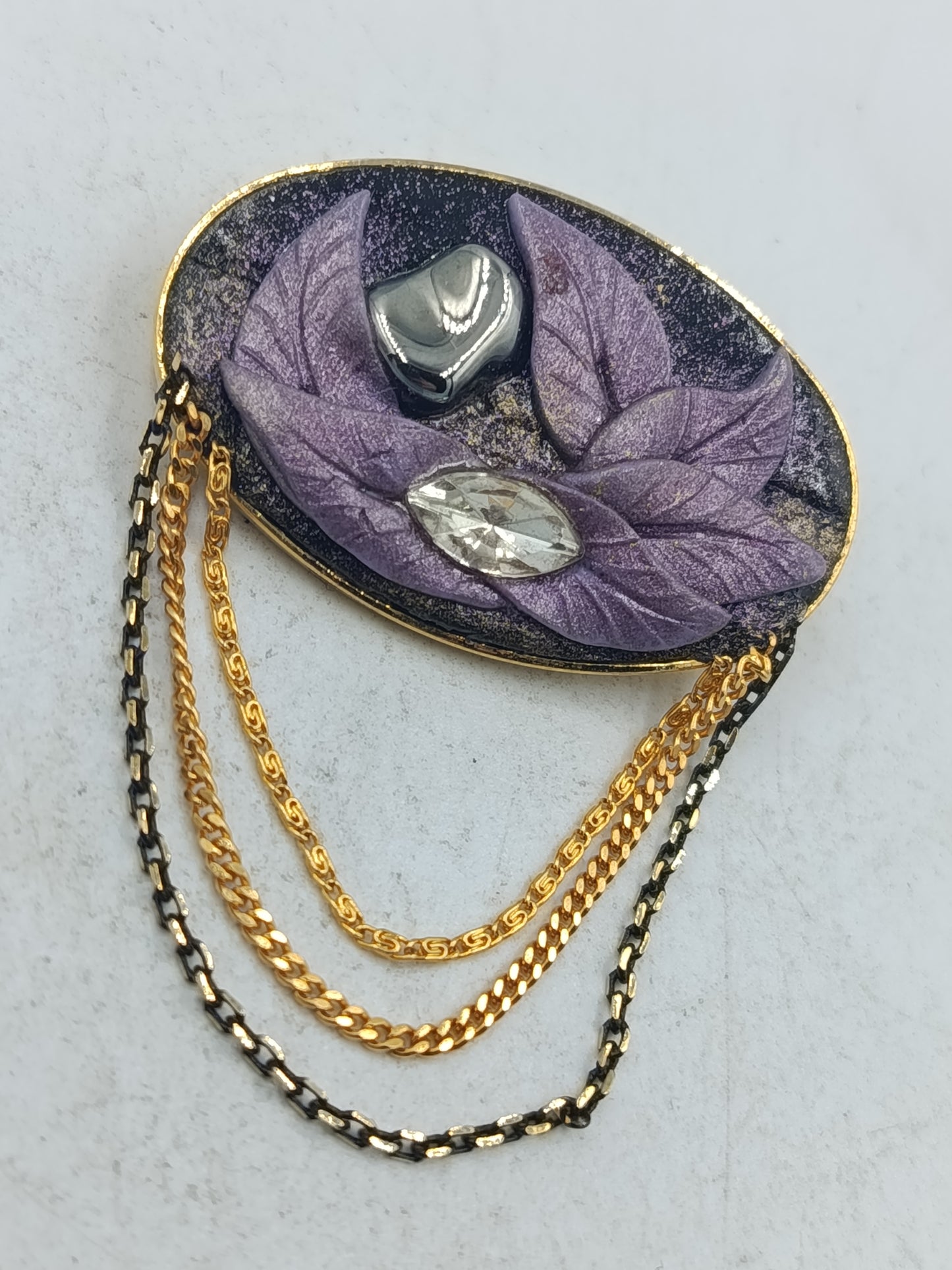 Ovale Brosche mit violettem Blattmotiv und goldfarbenen Zierketten