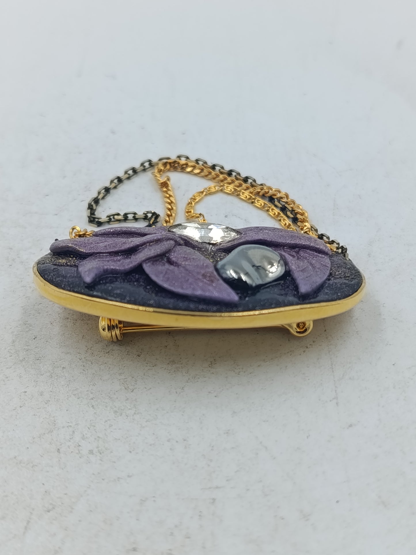 Ovale Brosche mit violettem Blattmotiv und goldfarbenen Zierketten