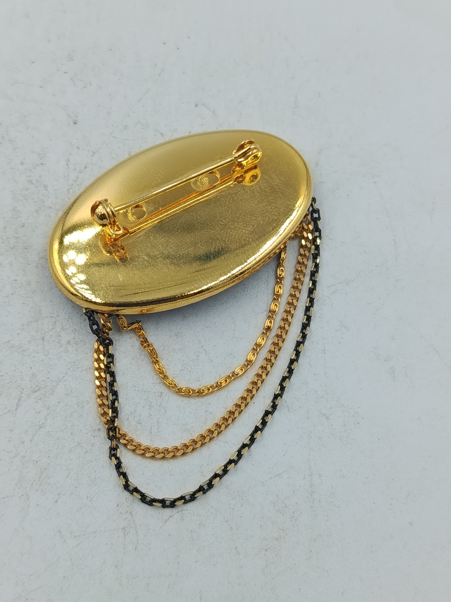 Ovale Brosche mit violettem Blattmotiv und goldfarbenen Zierketten