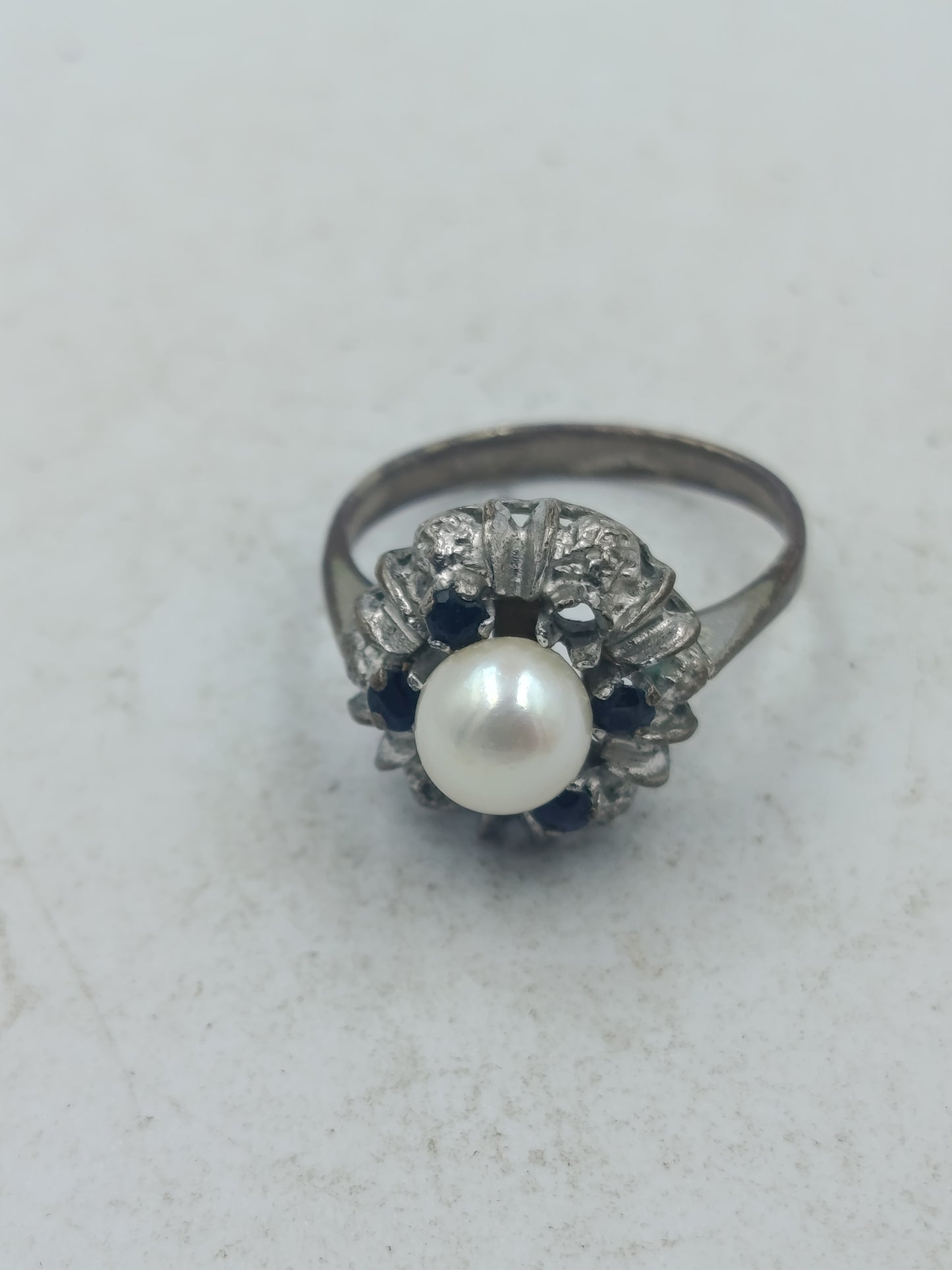 Perlenring mit dunkelblauen Steinen und kunstvoller silberfarbener Fassung im klassischen Stil