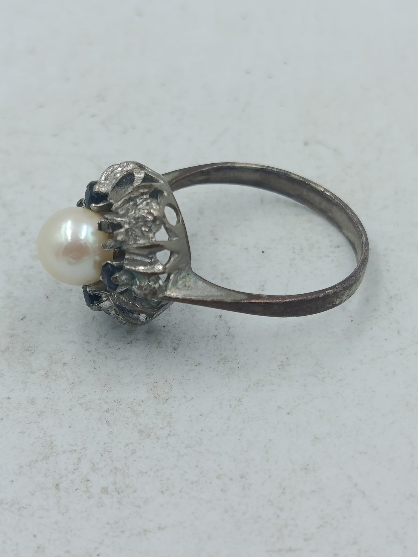 Perlenring mit dunkelblauen Steinen und kunstvoller silberfarbener Fassung im klassischen Stil