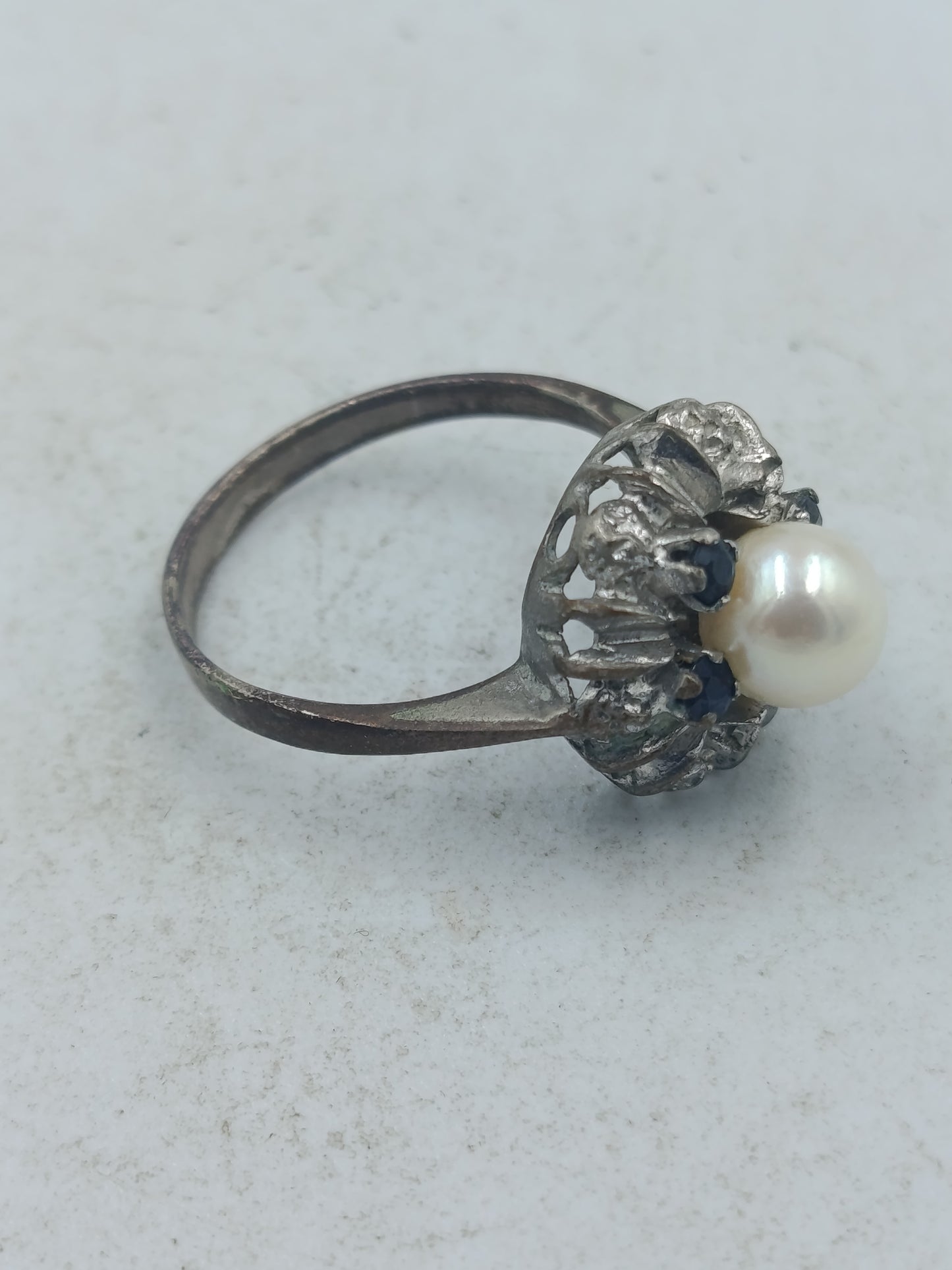 Perlenring mit dunkelblauen Steinen und kunstvoller silberfarbener Fassung im klassischen Stil