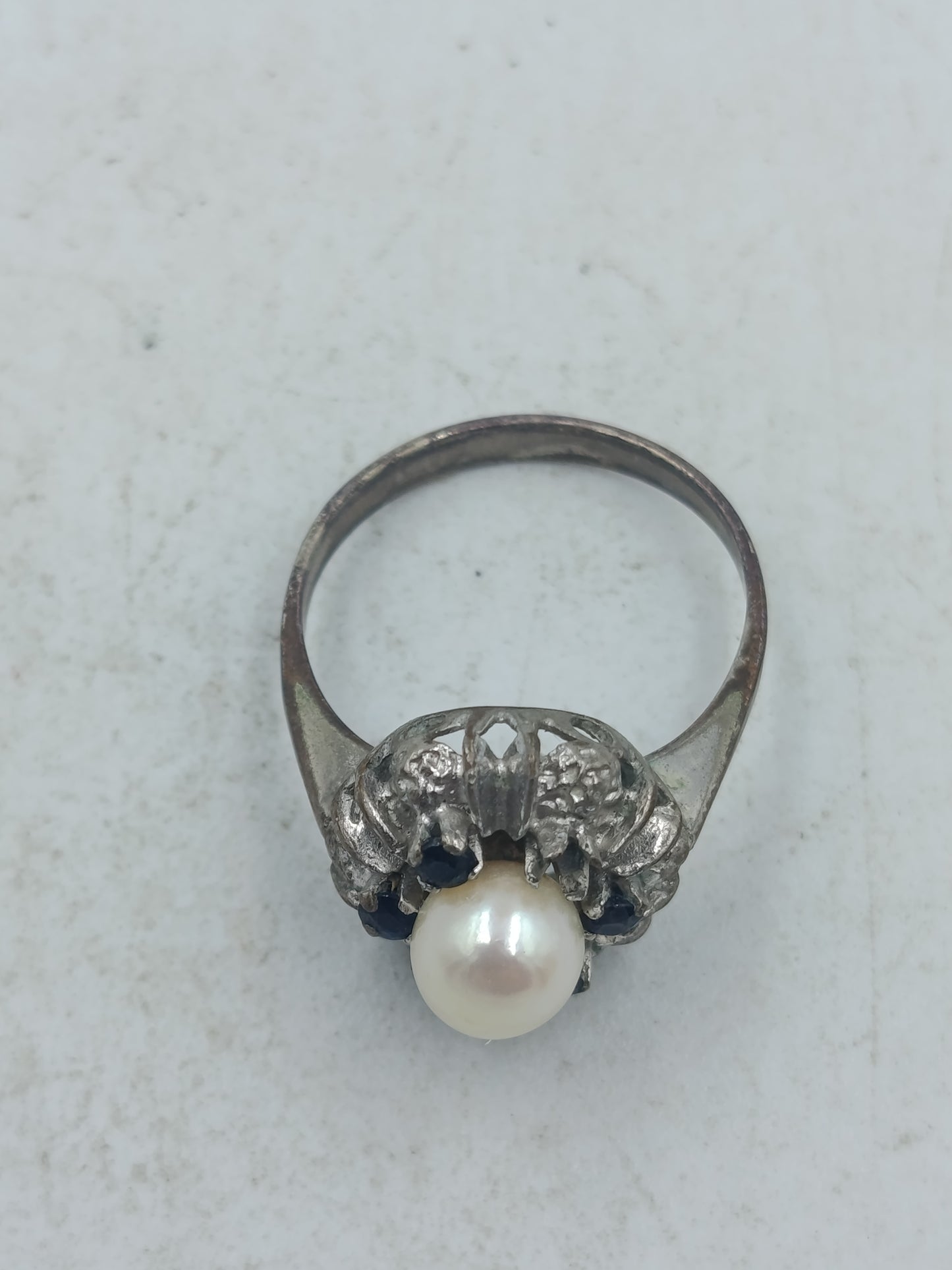 Perlenring mit dunkelblauen Steinen und kunstvoller silberfarbener Fassung im klassischen Stil