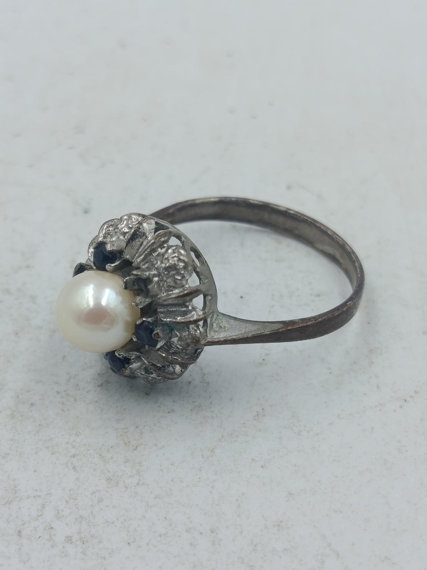 Perlenring mit dunkelblauen Steinen und kunstvoller silberfarbener Fassung im klassischen Stil