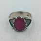 Silberring mit grossem rubinfarbenem Stein und kunstvoll verzierten Seitenflaechen im edlen Stil