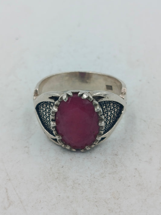 Silberring mit grossem rubinfarbenem Stein und kunstvoll verzierten Seitenflaechen im edlen Stil