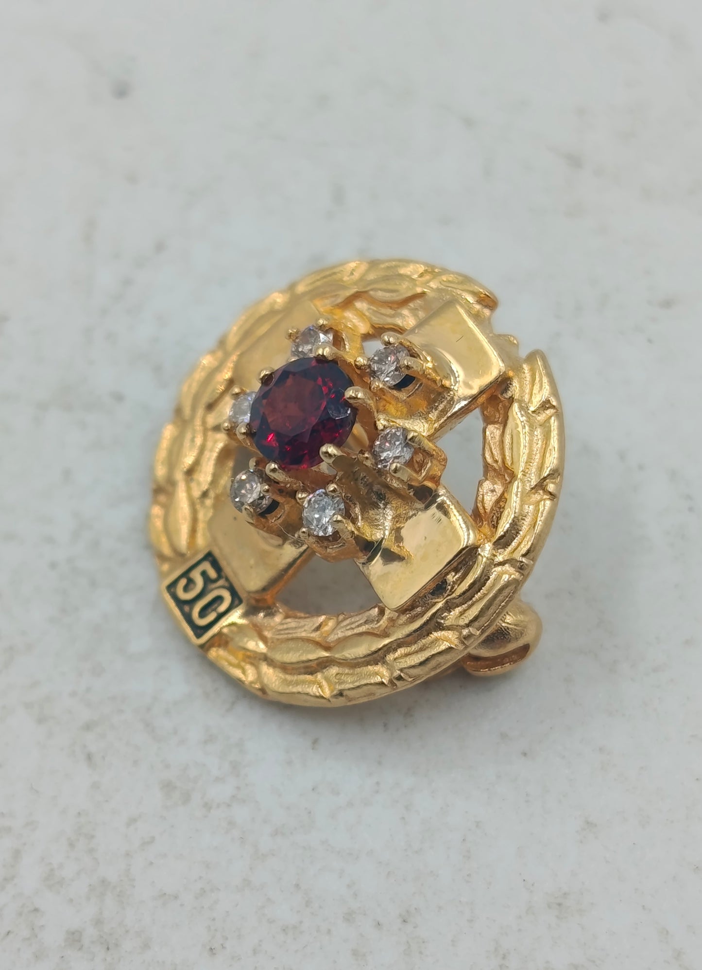 Goldfarbene Brosche mit rotem Mittelstein und funkelnden Akzenten im klassischen Stil