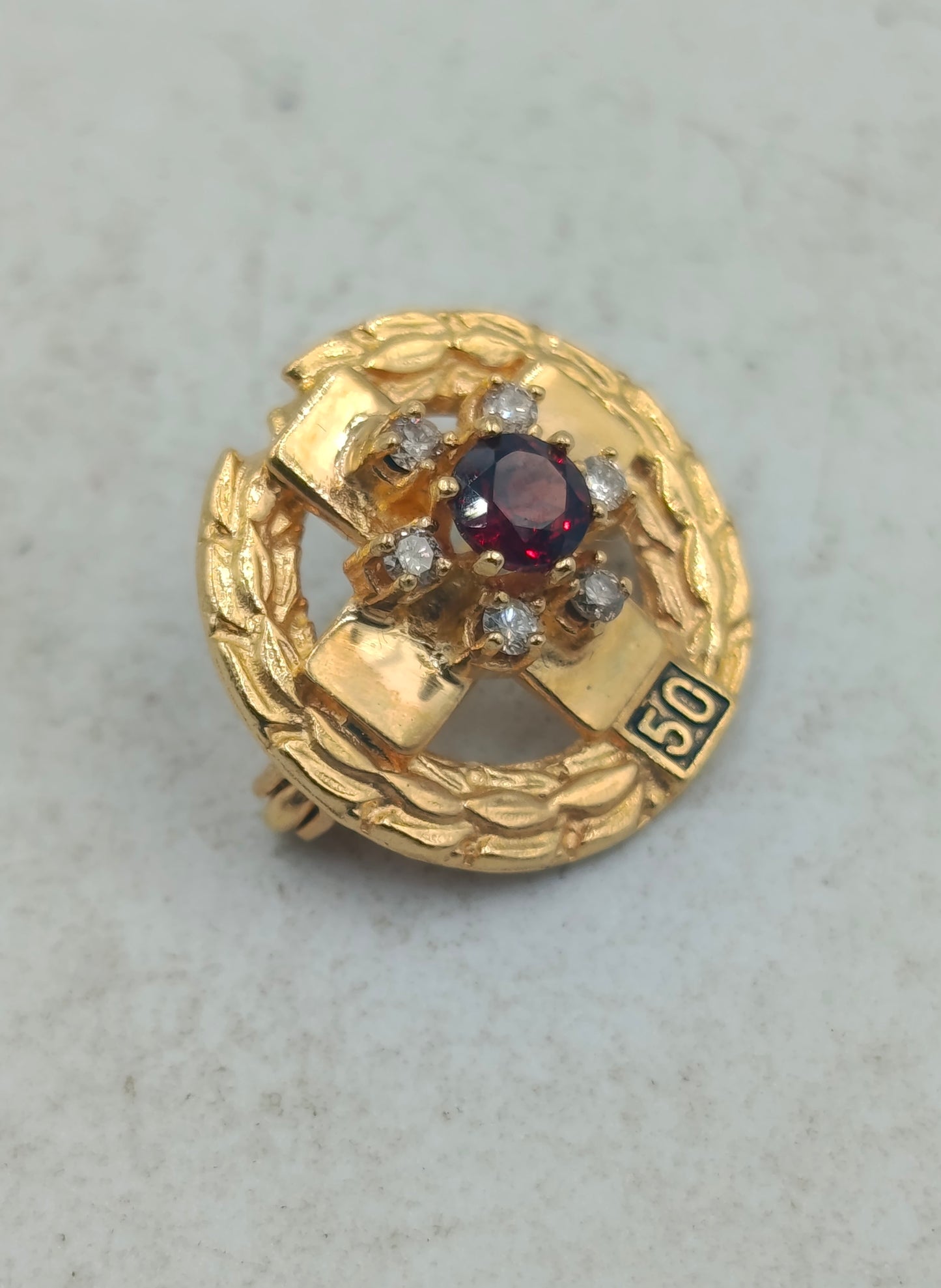 Goldfarbene Brosche mit rotem Mittelstein und funkelnden Akzenten im klassischen Stil