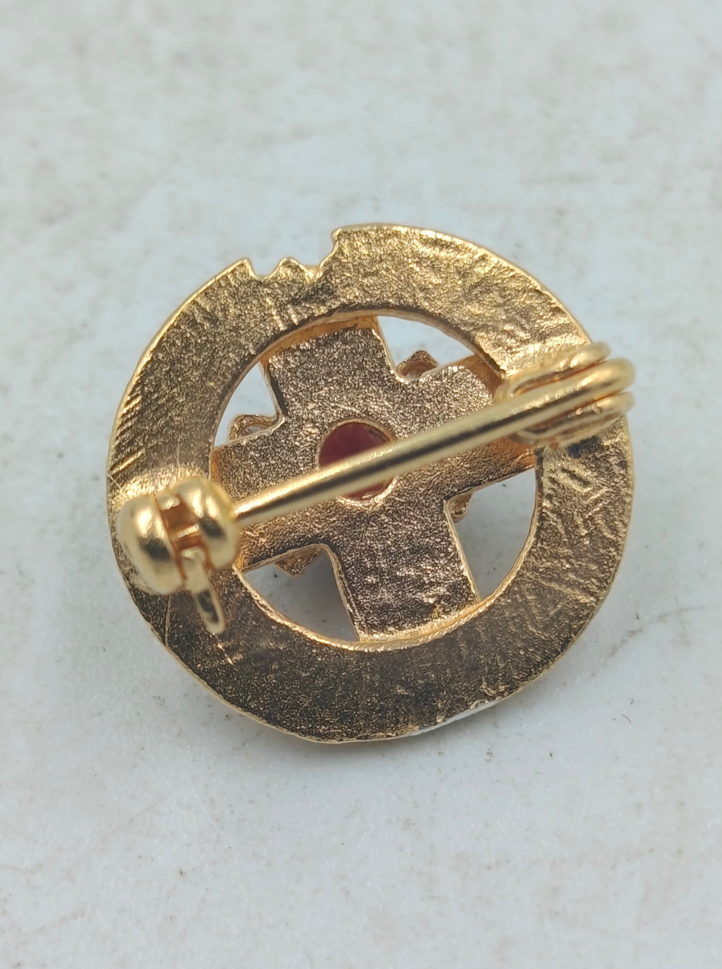 Goldfarbene Brosche mit rotem Mittelstein und funkelnden Akzenten im klassischen Stil