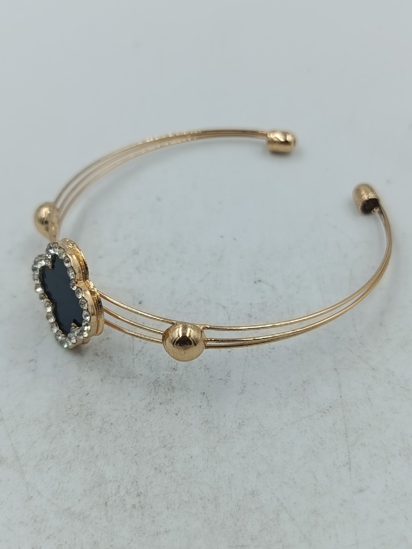 Elegantes Armreif Armband in Goldoptik mit schwarzem Kleeblatt und funkelndem Strassbesatz