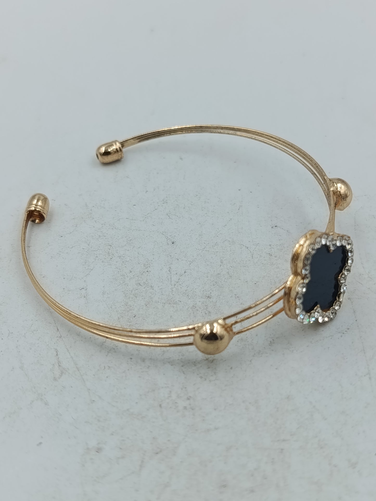 Elegantes Armreif Armband in Goldoptik mit schwarzem Kleeblatt und funkelndem Strassbesatz