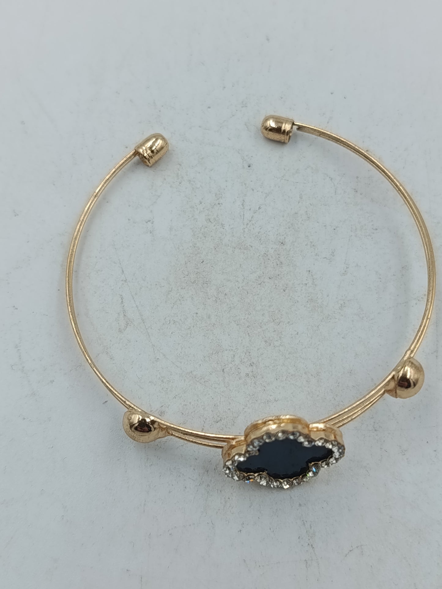 Elegantes Armreif Armband in Goldoptik mit schwarzem Kleeblatt und funkelndem Strassbesatz
