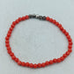Feines elastisches Perlenarmband in kräftigem Rot mit dezenten dunklen Akzentperlen