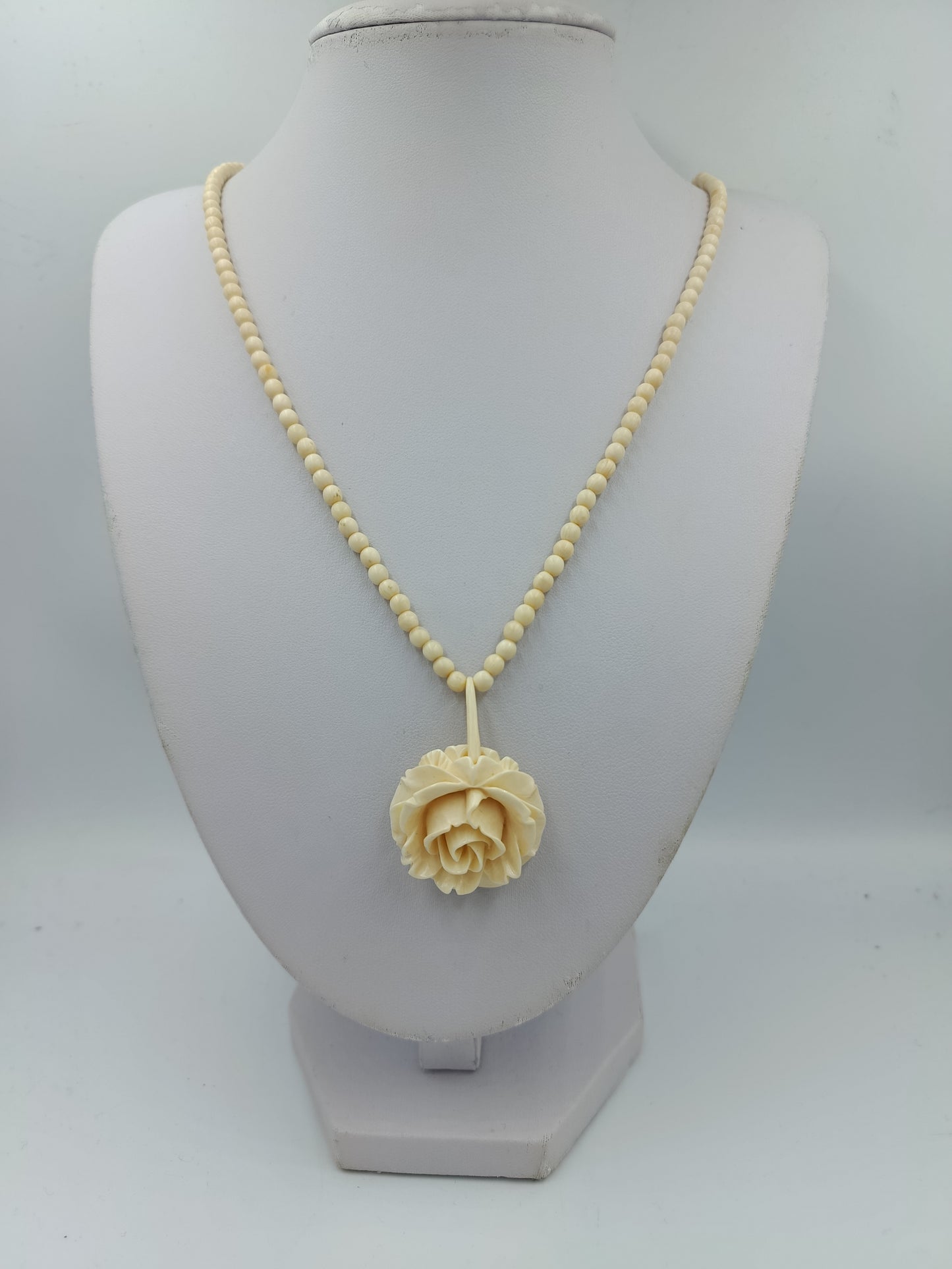 Elegante Kette in Cremeoptik mit fein geschnitzter Blütenform als stilvoller Blickfang