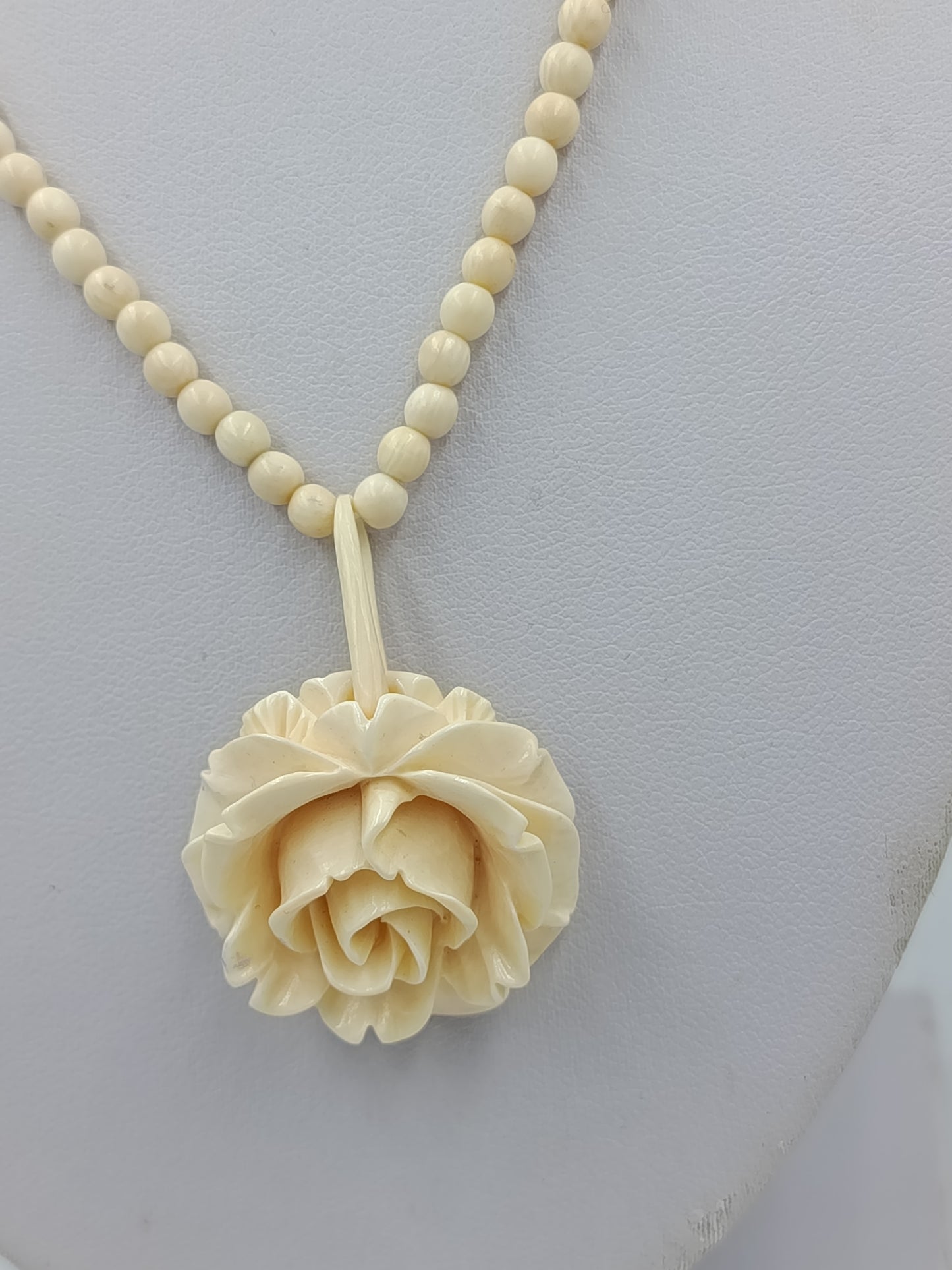 Elegante Kette in Cremeoptik mit fein geschnitzter Blütenform als stilvoller Blickfang