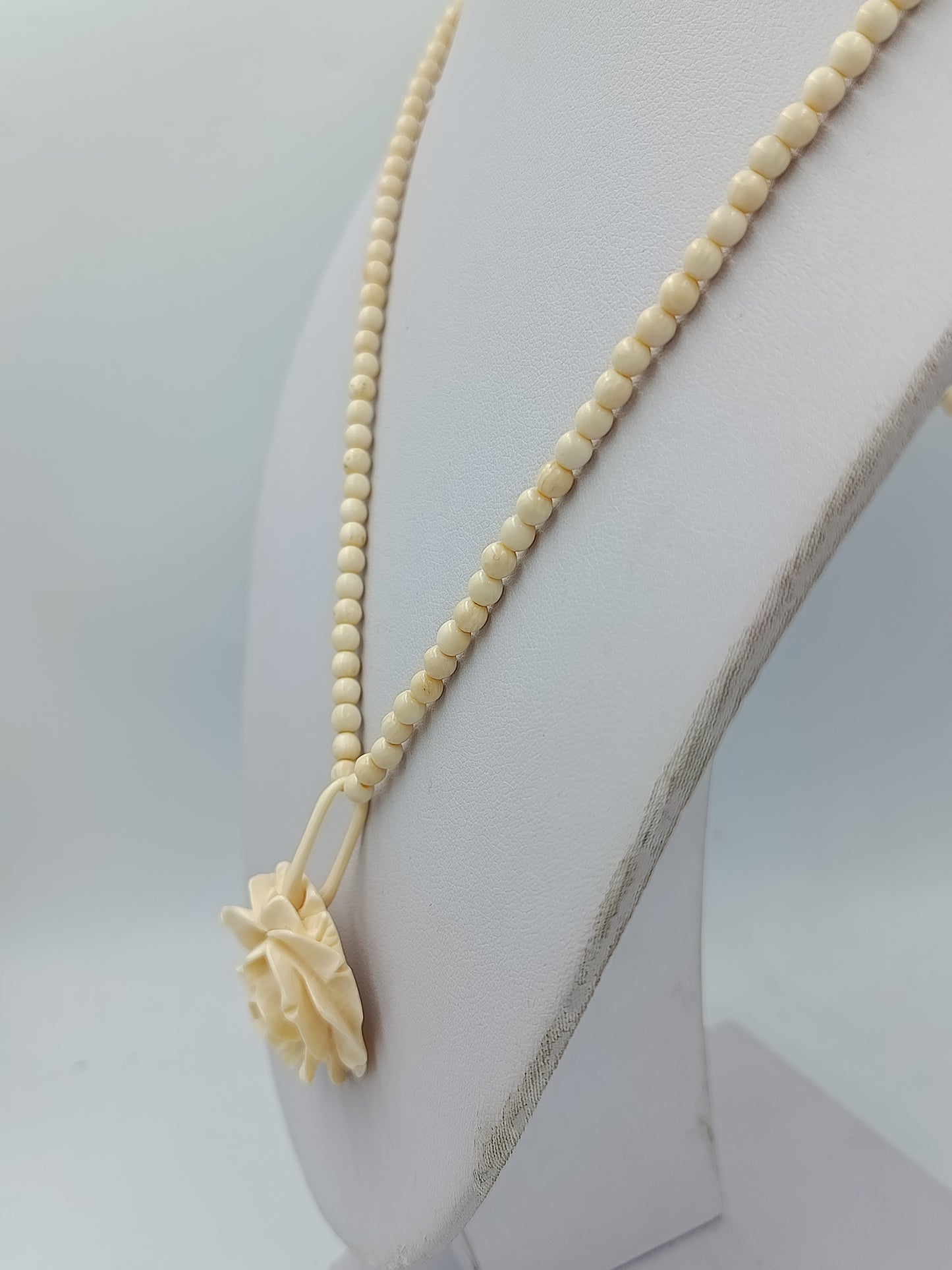 Elegante Kette in Cremeoptik mit fein geschnitzter Blütenform als stilvoller Blickfang