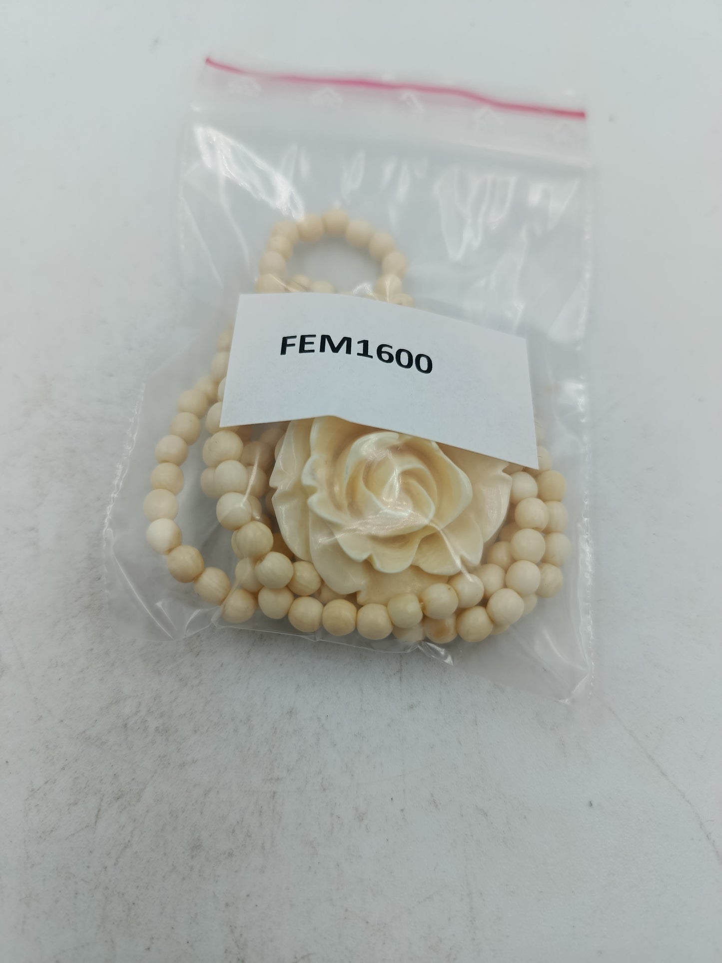 Elegante Kette in Cremeoptik mit fein geschnitzter Blütenform als stilvoller Blickfang