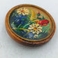 Runde Holz Brosche mit handgemaltem Blumenmotiv in warmen Naturfarben