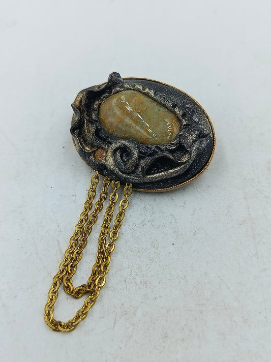 Goldfarbene Brosche mit ovalem Naturstein und dekorativer Kette im Vintage Stil