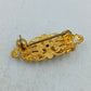 Goldfarbene Brosche mit filigranem Ornamentdesign und funkelnden Steinen