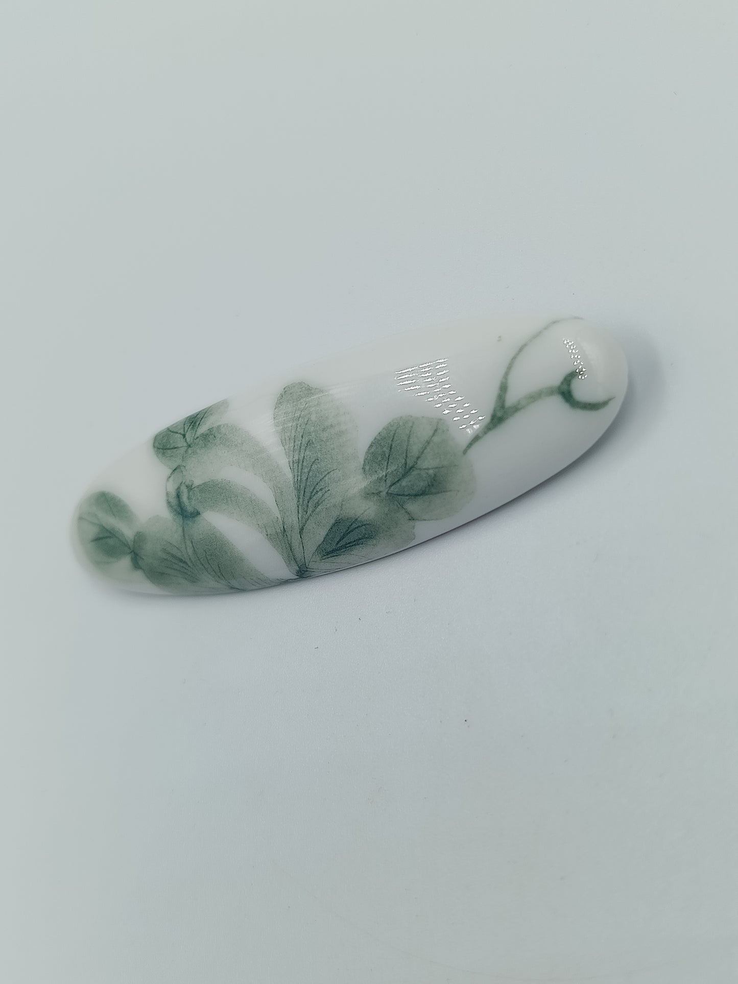 Vintage Brosche länglich mit floralem Dekor in Grün auf weißem Untergrund