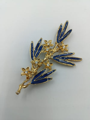 Elegante Brosche mit blauen Emailleblättern und funkelnden Blüten in Goldoptik