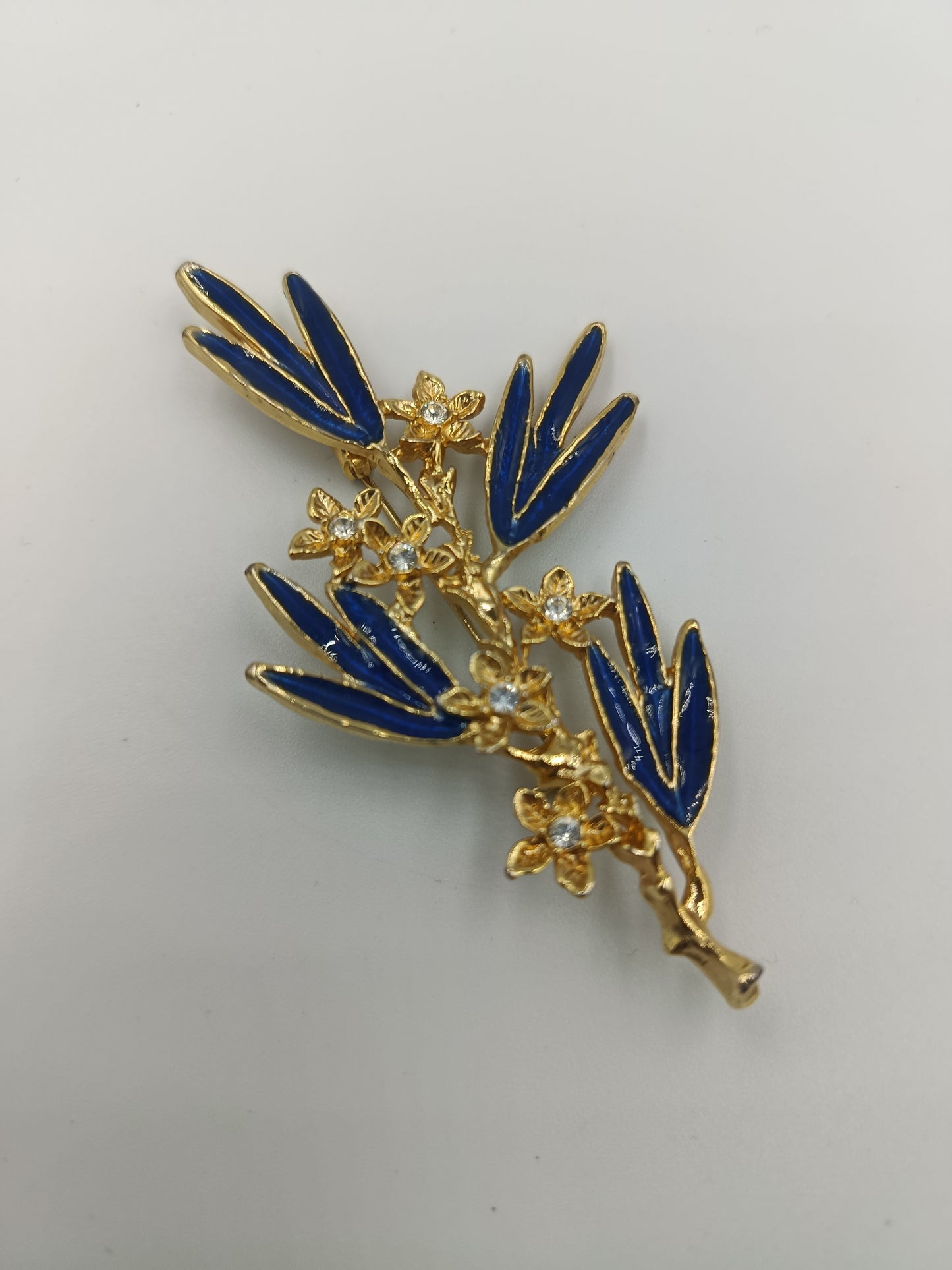 Elegante Brosche mit blauen Emailleblättern und funkelnden Blüten in Goldoptik